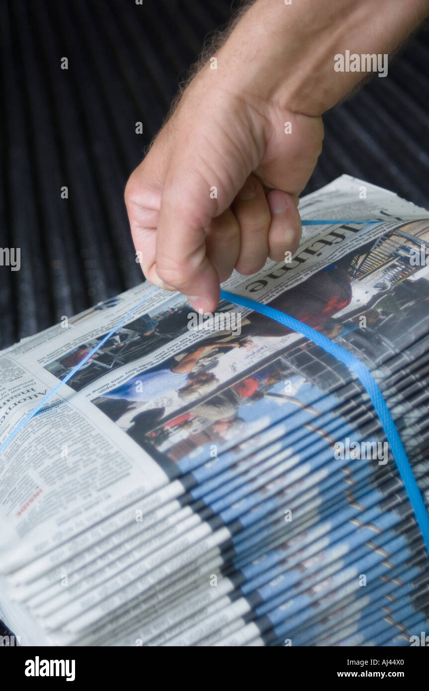 Newspaper carrier lifting a bundle of newspapers Stock Photo Alamy