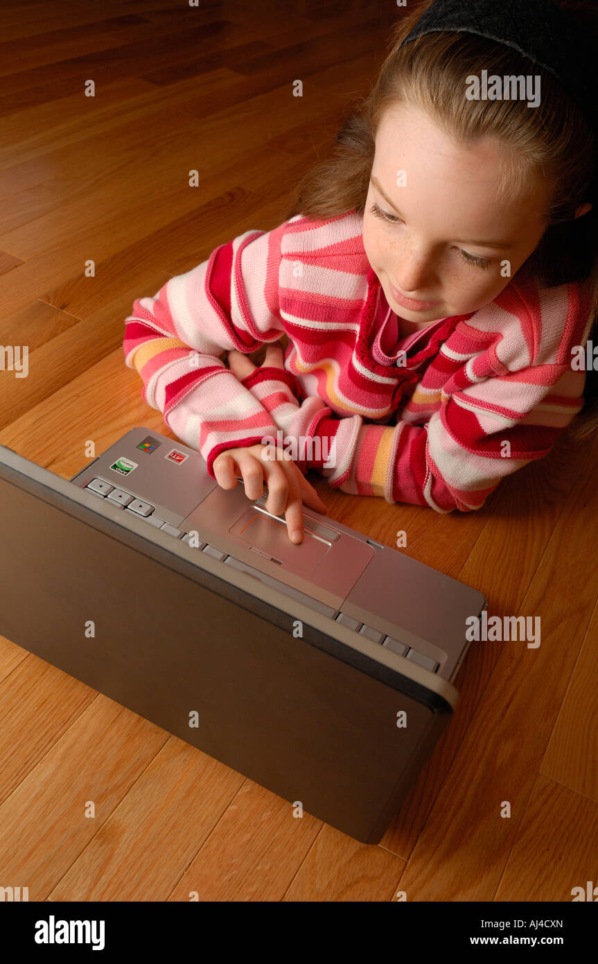 Young Girl Age 8 Lying On The Floor Working On A Laptop Computer