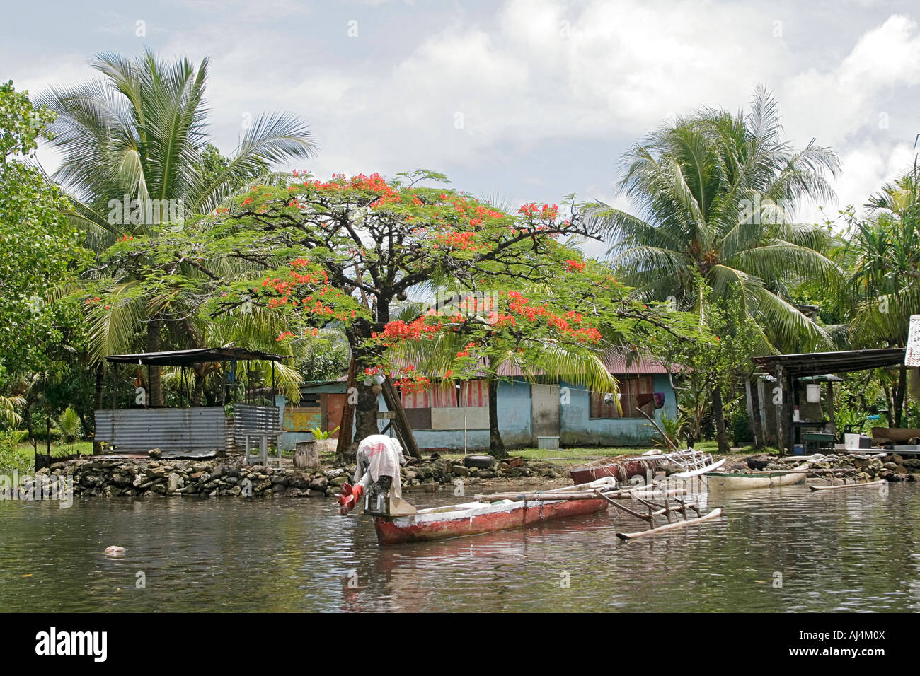Typical home with outrigger canoes out front in the more urban area of Kosrae on Finkos River in Micronesia Stock Photo