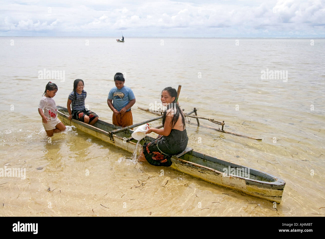 Local children play in shallow water with traditional hand carved