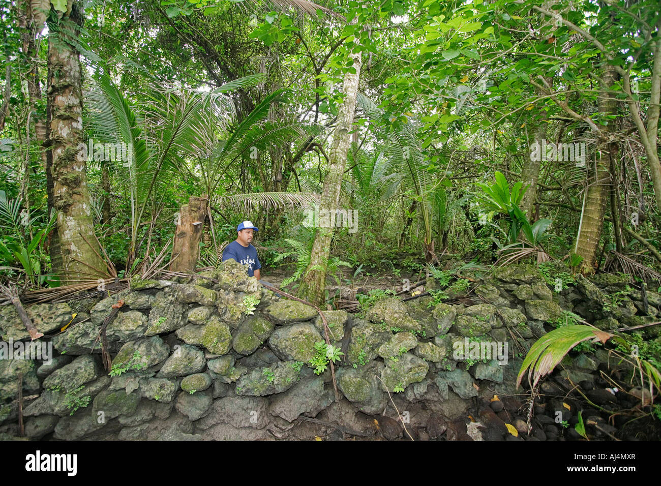 Local man stands in coral blocks that make up what is left of ancient habitation ruins in Walung Stock Photo