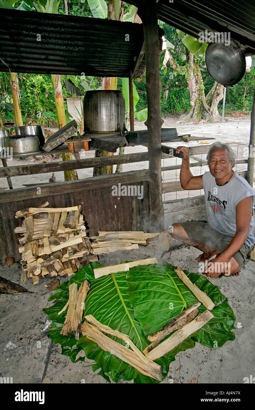 Middle aged local man sits in his kitchen hut by his uhm a traditional pit oven used to cook food Stock Photo