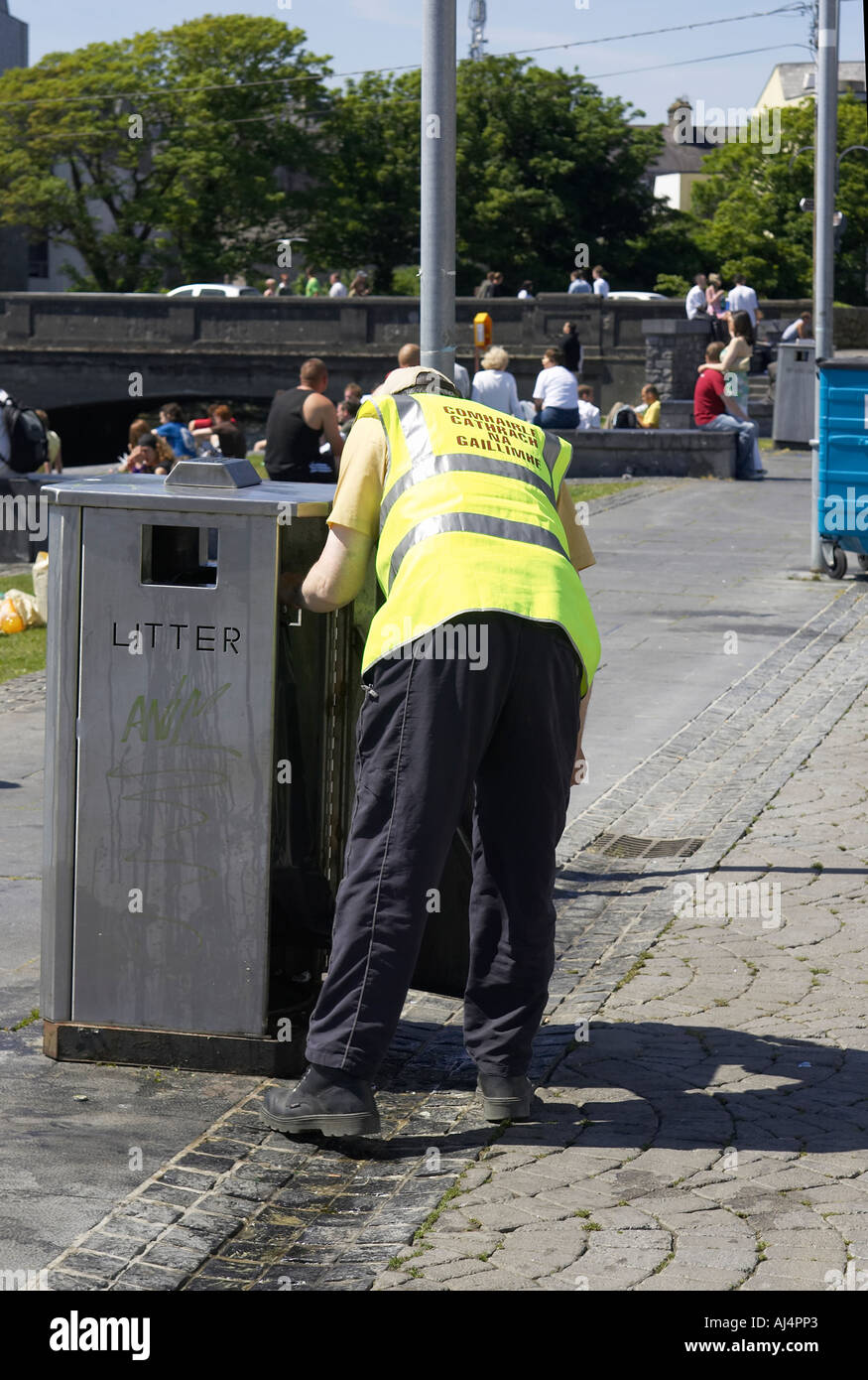 galway city council worker in luminous yellow clothing with irish gaelic writing empties litter bin Galway city Stock Photo