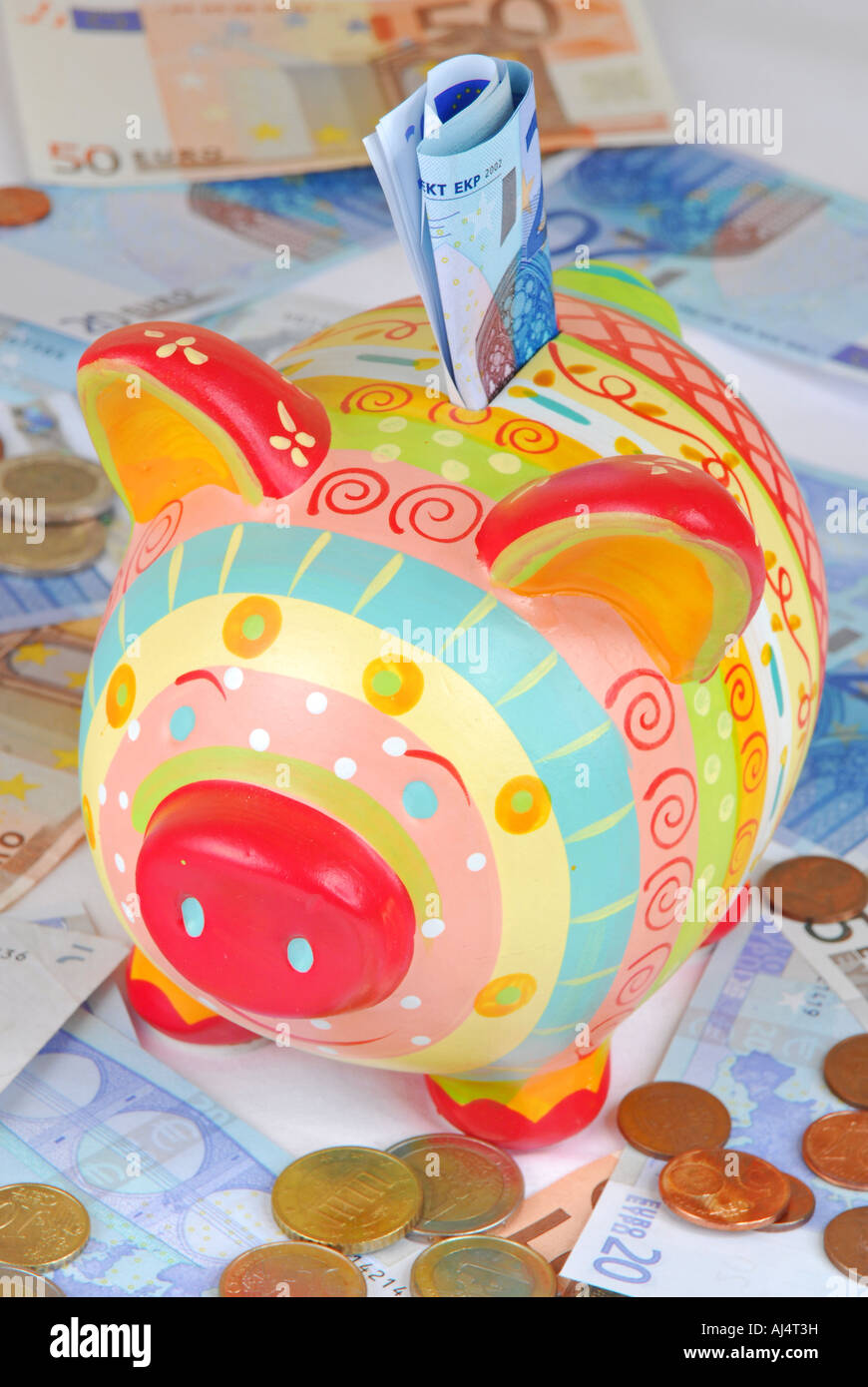 A colourful piggy bank on Euro coins and notes Stock Photo - Alamy
