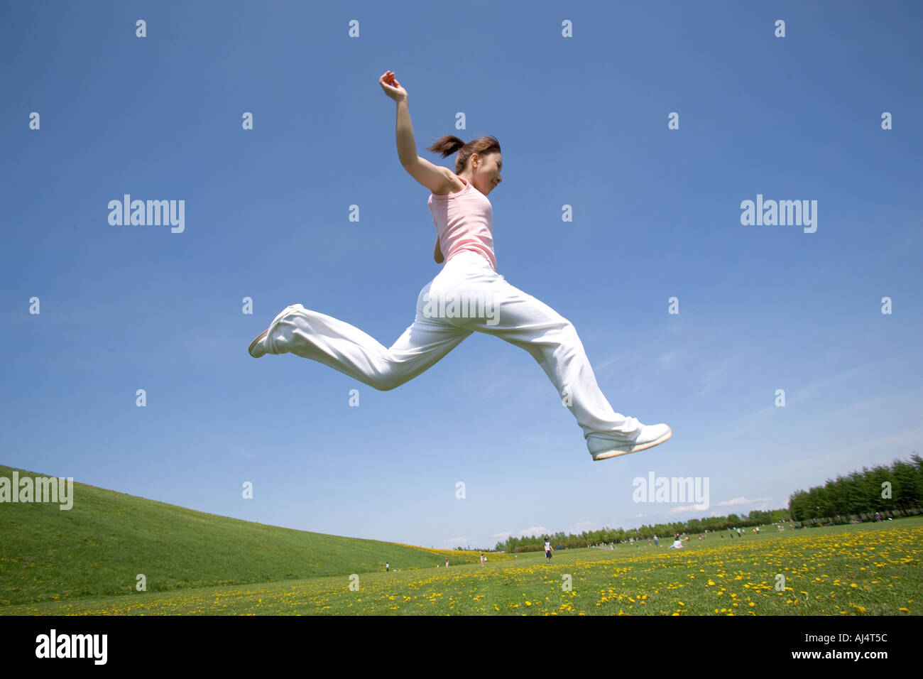 Young woman leaping in field Stock Photo