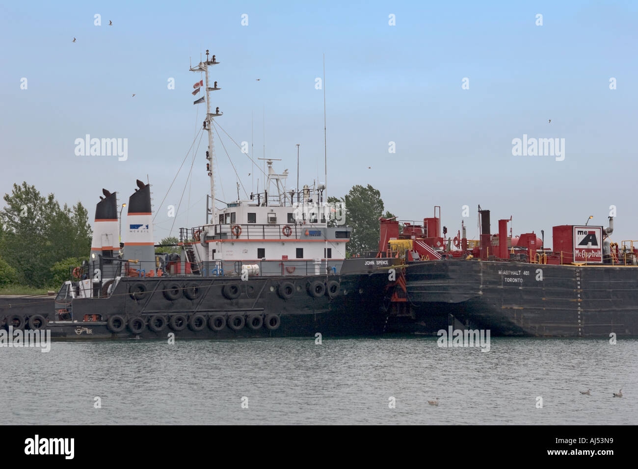 A tugboat tows a barge through a canal Stock Photo