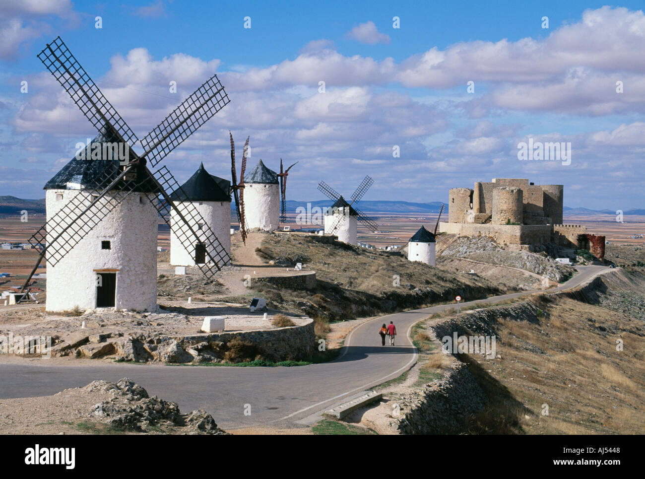 Windmills and castle overlooking the plains of Castilla La Mancha Spain Couple walking together. Travel in Spain tourism culture Stock Photo