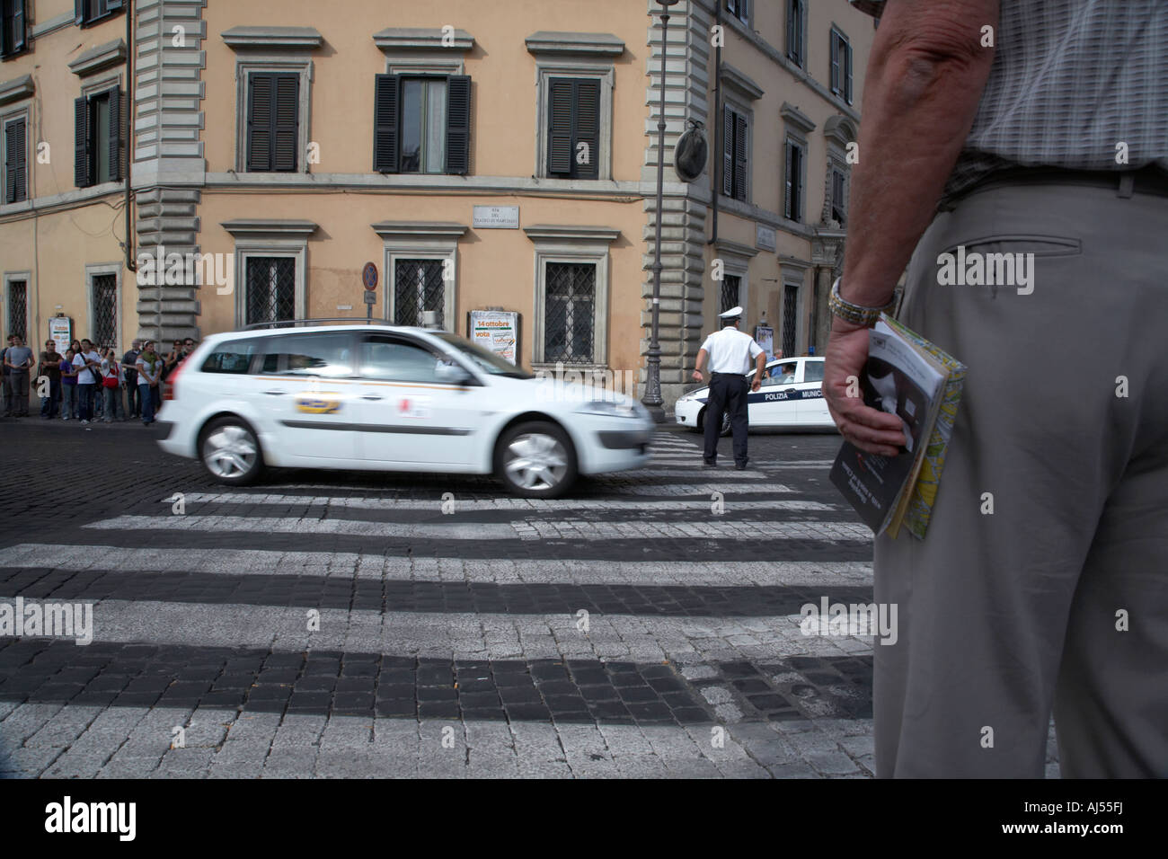 tourist waits at crossing as Roman Municipal policeman directs traffic at a pedestrian crossing in the Via Teatro Marcello Rome Stock Photo