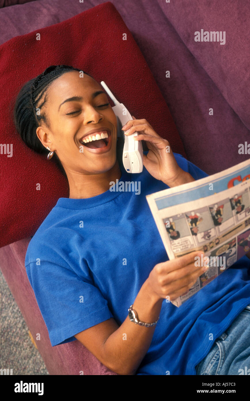 African American woman laughing talking on phone reading comics Stock Photo