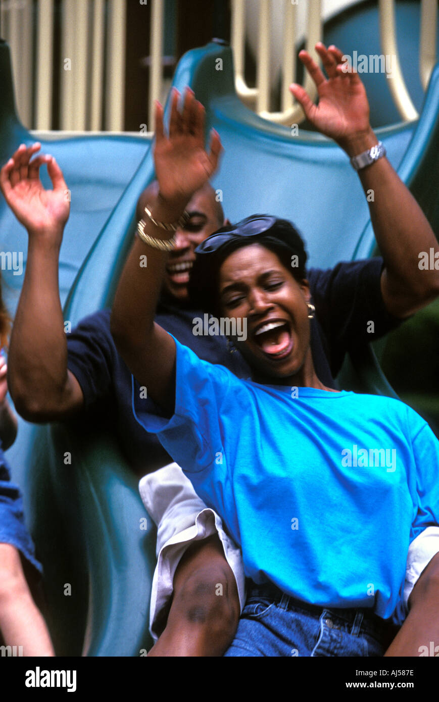 African American couple playing on playground slide Stock Photo