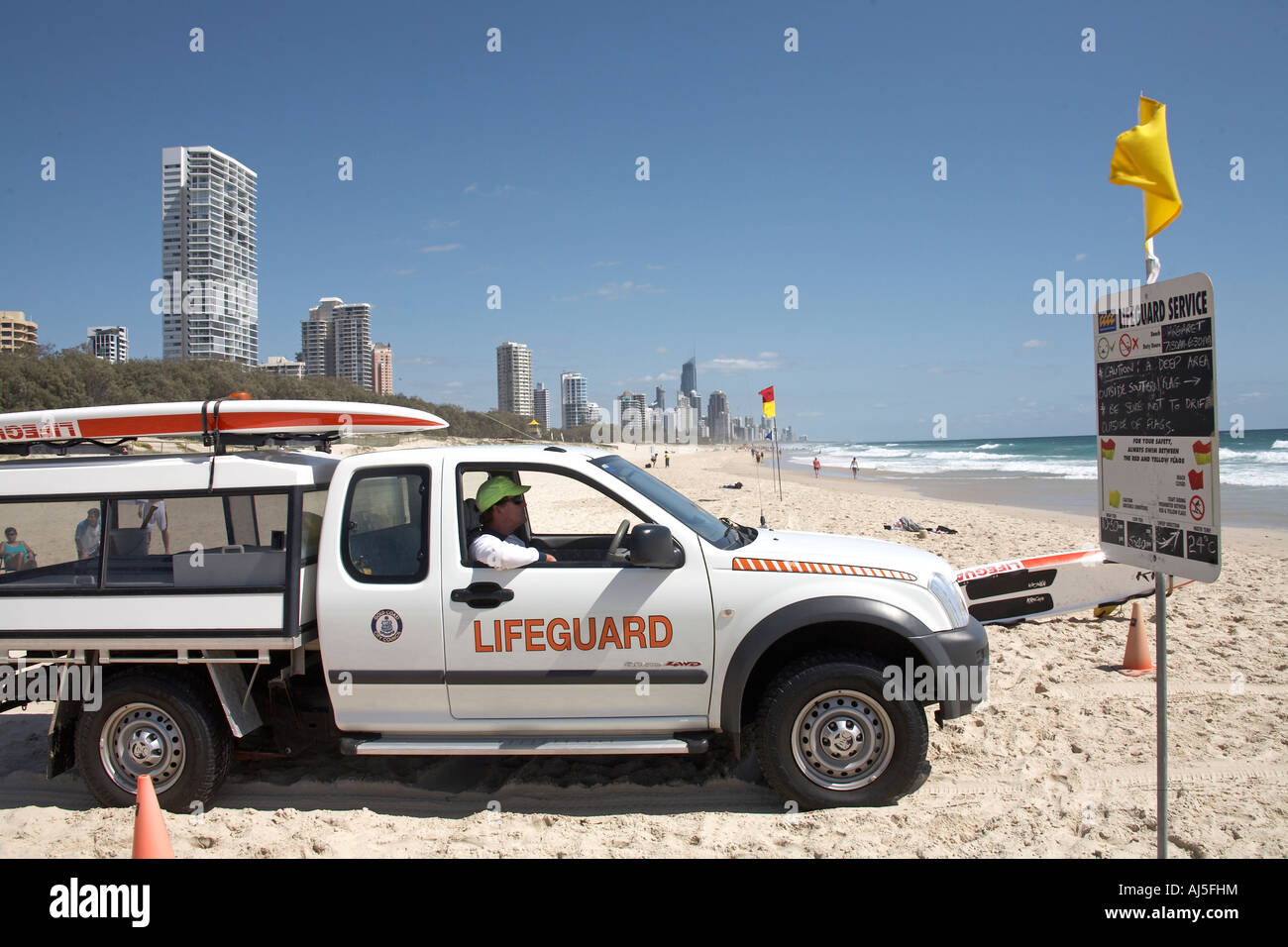 Lifeguard in ute pick up truck on the beach with warning notice in Surfers Paradise Queensland QLD Australia Stock Photo