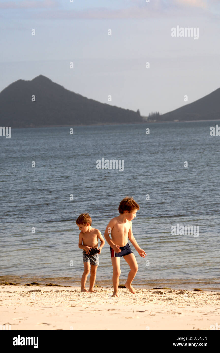 Two young boys children brothers playing by water on Jimmy s Beach Hawks Nest Port Stephens New South Wales NSW Australia Stock Photo