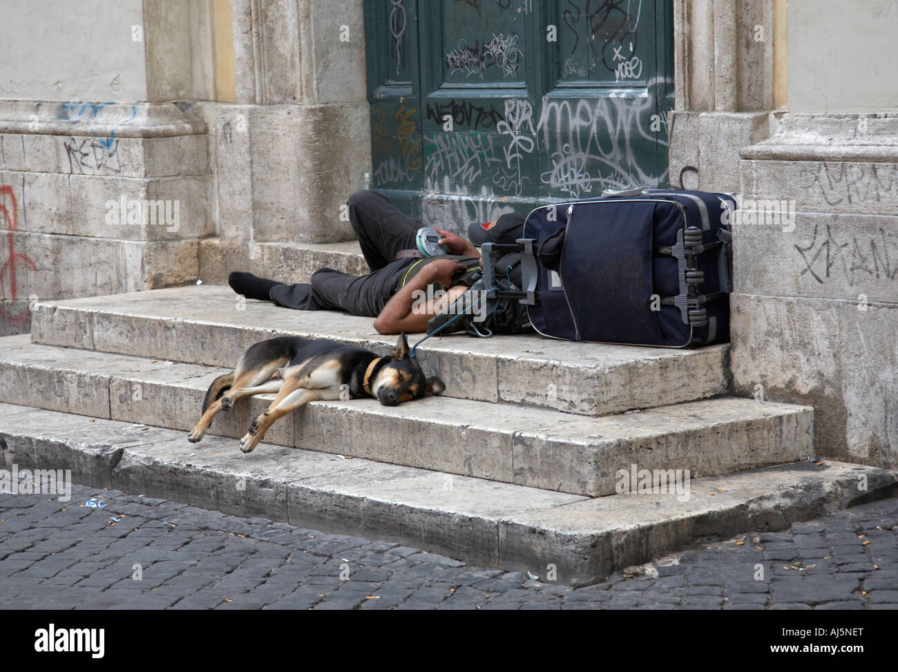 man with down and out appearance with dog and luggage sleeping on the steps  of a church in trastevere Rome Lazio Italy Stock Photo - Alamy