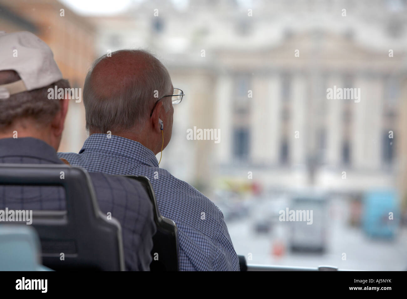 Tourist sitting on a tour bus listening to tour guide on headphones as it approaches the Basilica of St Peters Rome Lazio Italy Stock Photo