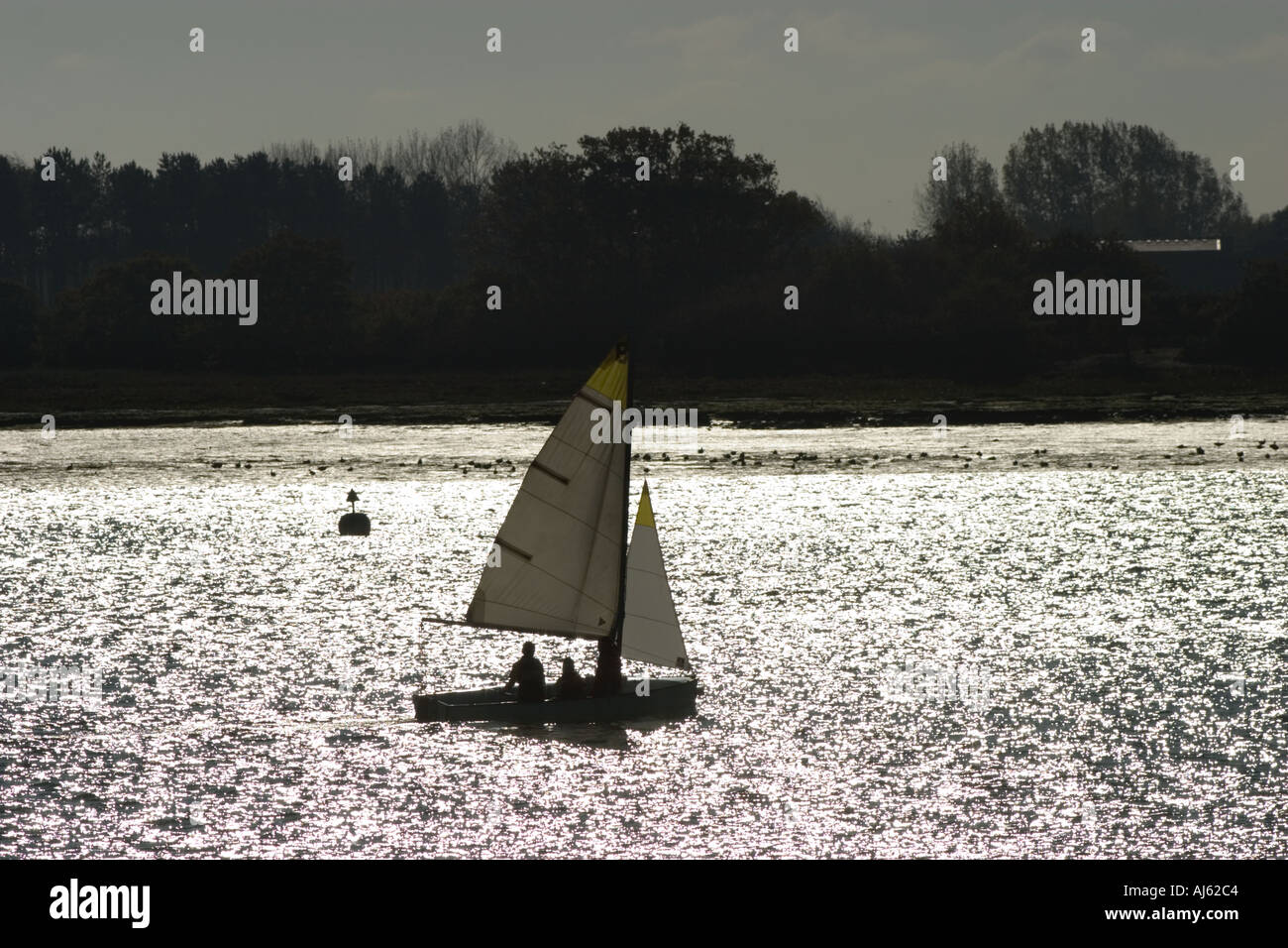 Sailing dinghy silhouetted against water Stock Photo - Alamy