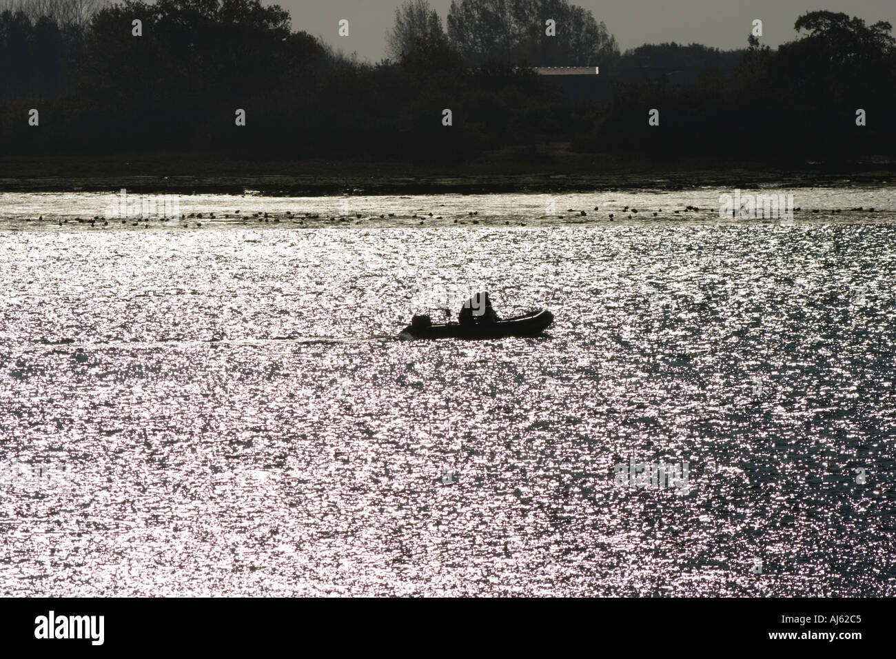 Two men in a rubber dinghy silhouetted against water Stock Photo - Alamy