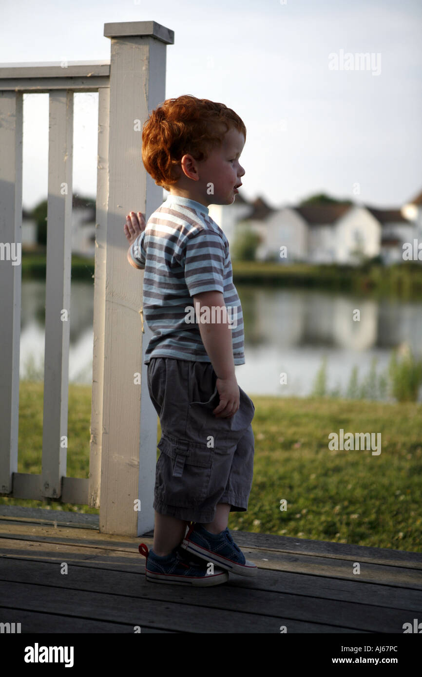 Cotswolds Water Park located at South Cerney near Cirencester Gloucestershire Boy standing on decking pondering Stock Photo