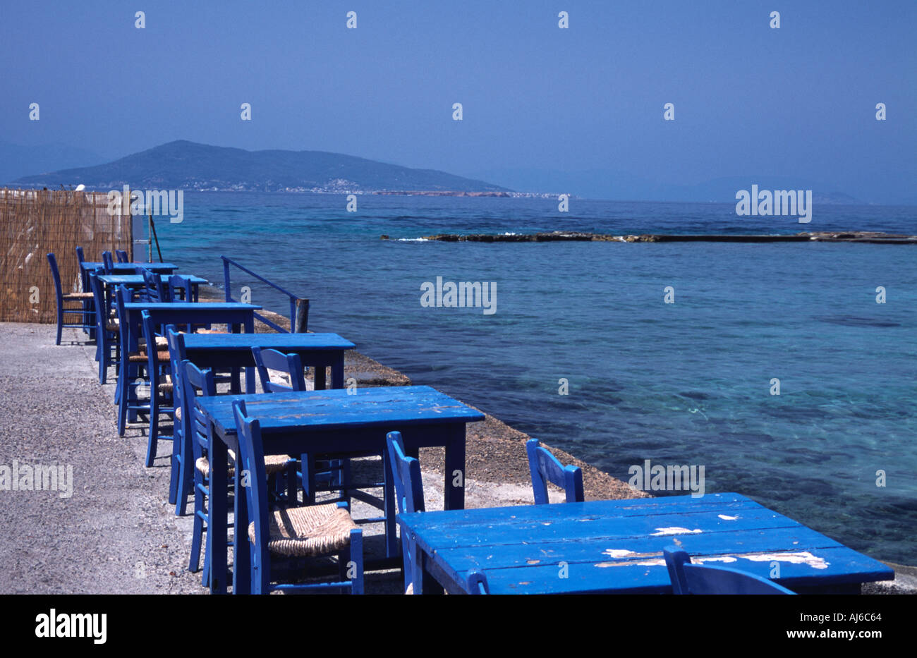 Tables waiting for clients at Aegina Island beach restaurant Greece Stock Photo