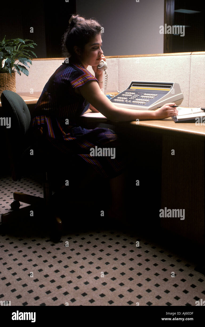 Female receptionist on phone in office cubicle Stock Photo