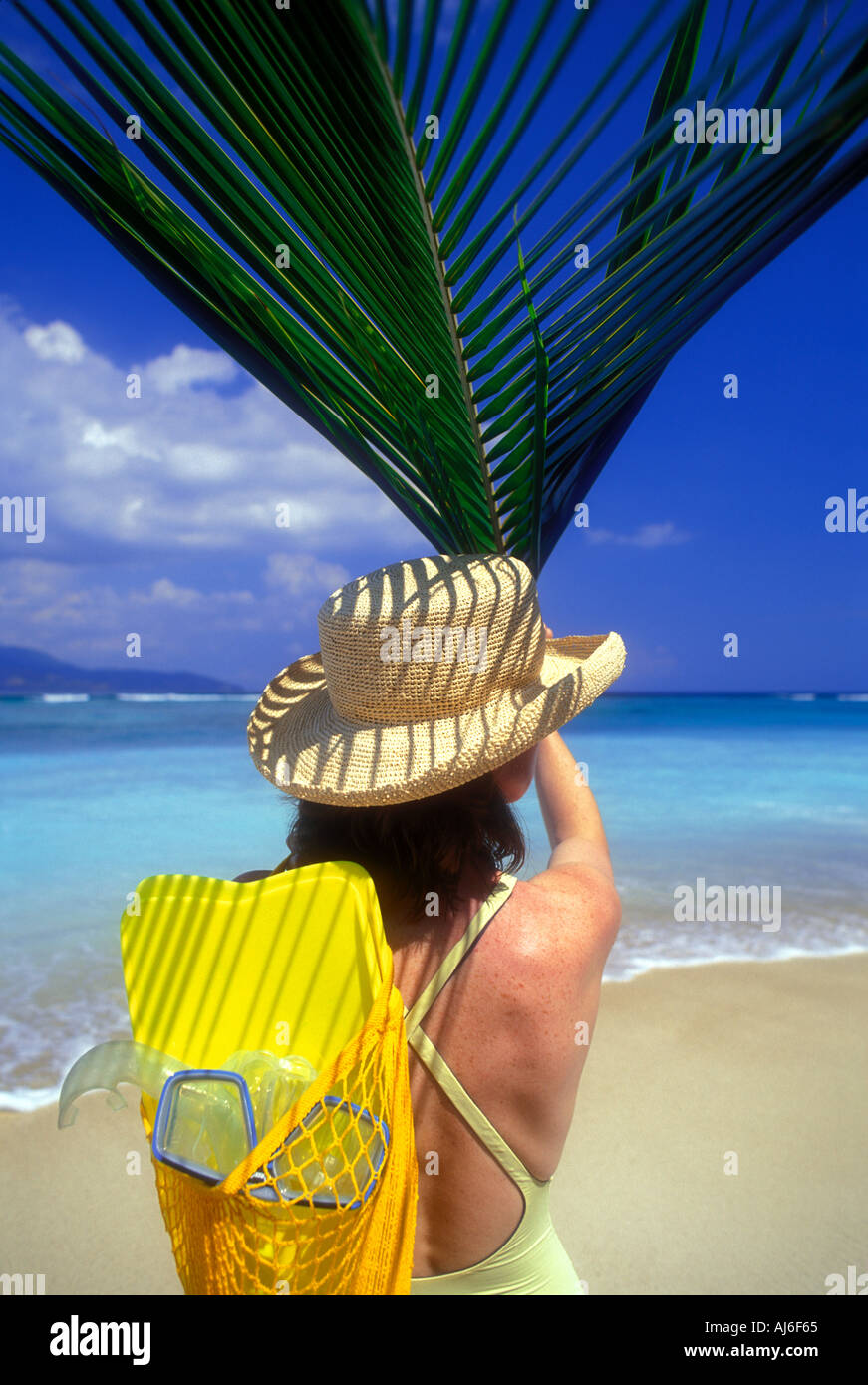 Woman holding palm frond leaf over head on the island of Lombok in Indonesia Southeast Asia Model Released Image Stock Photo