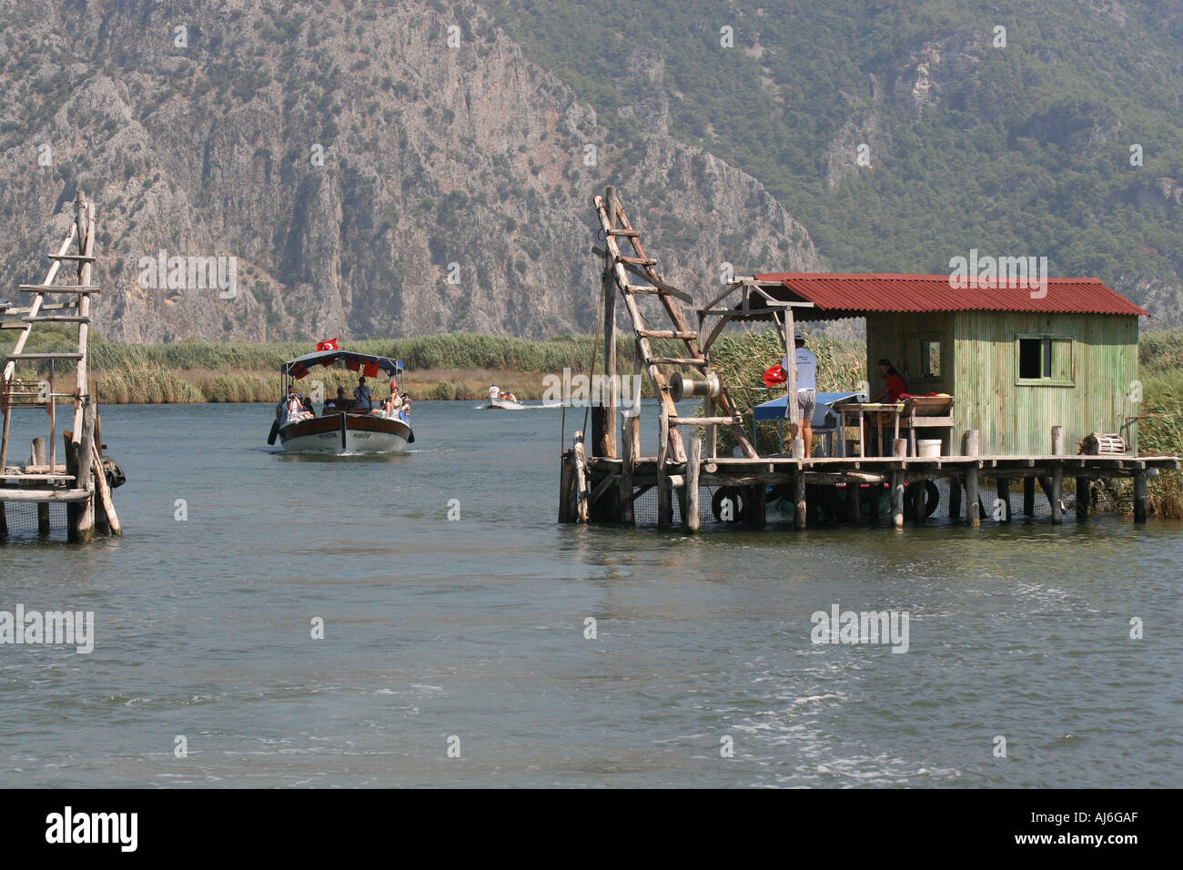 Boat on the River Dalyan Cayi passing through a fishing barrier southern Turkey  Stock Photo