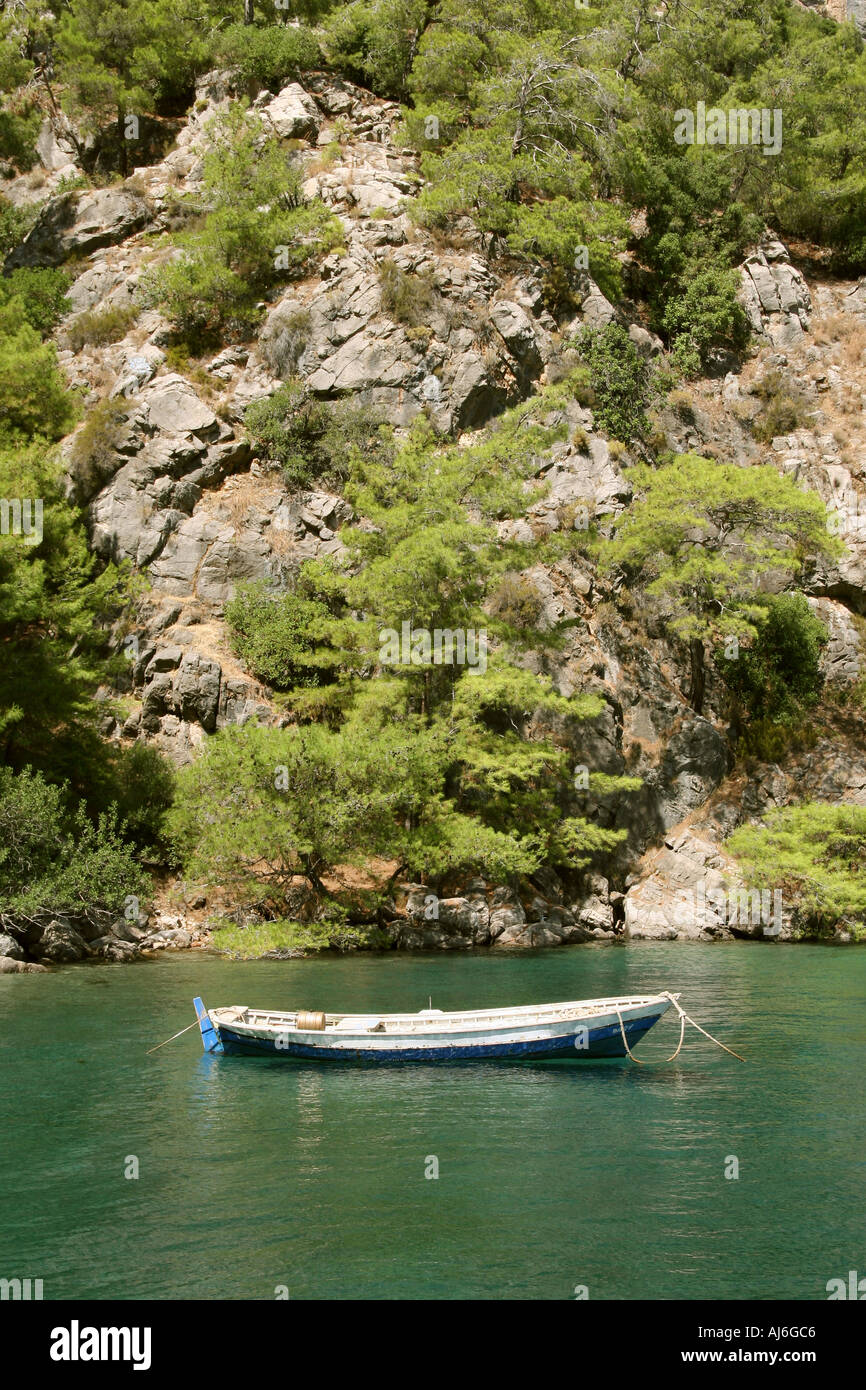 Small traditional fishing boat moored beneath a cliff near Fethiye Turkey  Stock Photo