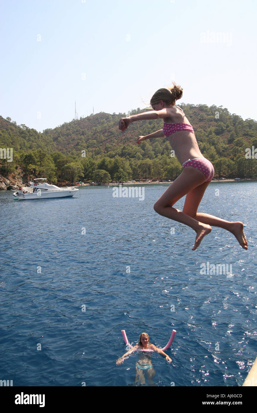 Young girl jumping into the sea from a boat watched by another girl  Stock Photo