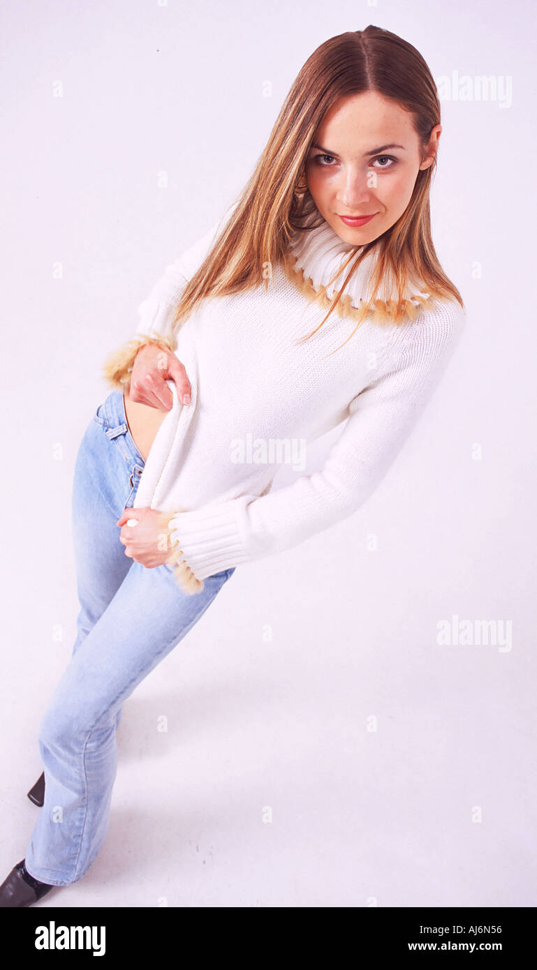 Young smiling woman wearing white jumper standing. Stock Photo