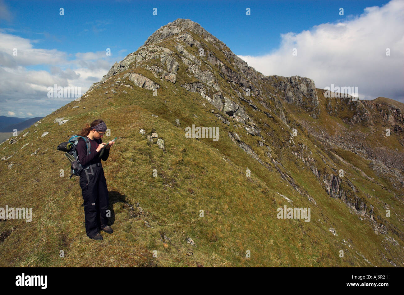 A hillwalker taking bearings near the summit of Streap in the Scottish Highlands Stock Photo