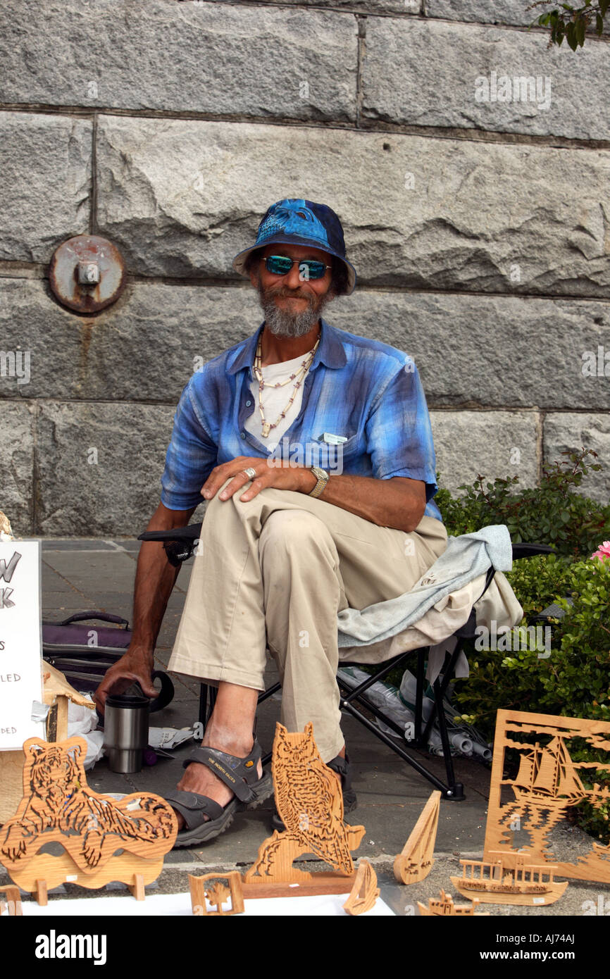 An artist selling wooden carvings in downtown Victoria during Canada ...