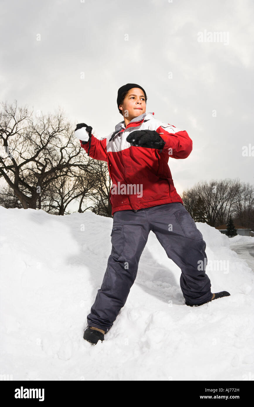 Boy standing in snow throwing snowball Stock Photo Alamy