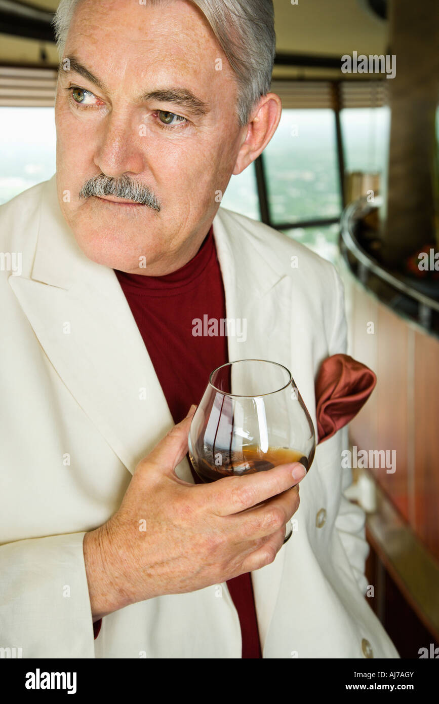 Mature Caucasian man in suit holding snifter of brandy Stock Photo Alamy