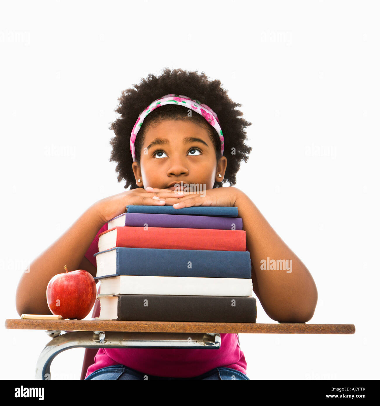 African American girl sitting in school desk with large stack of books