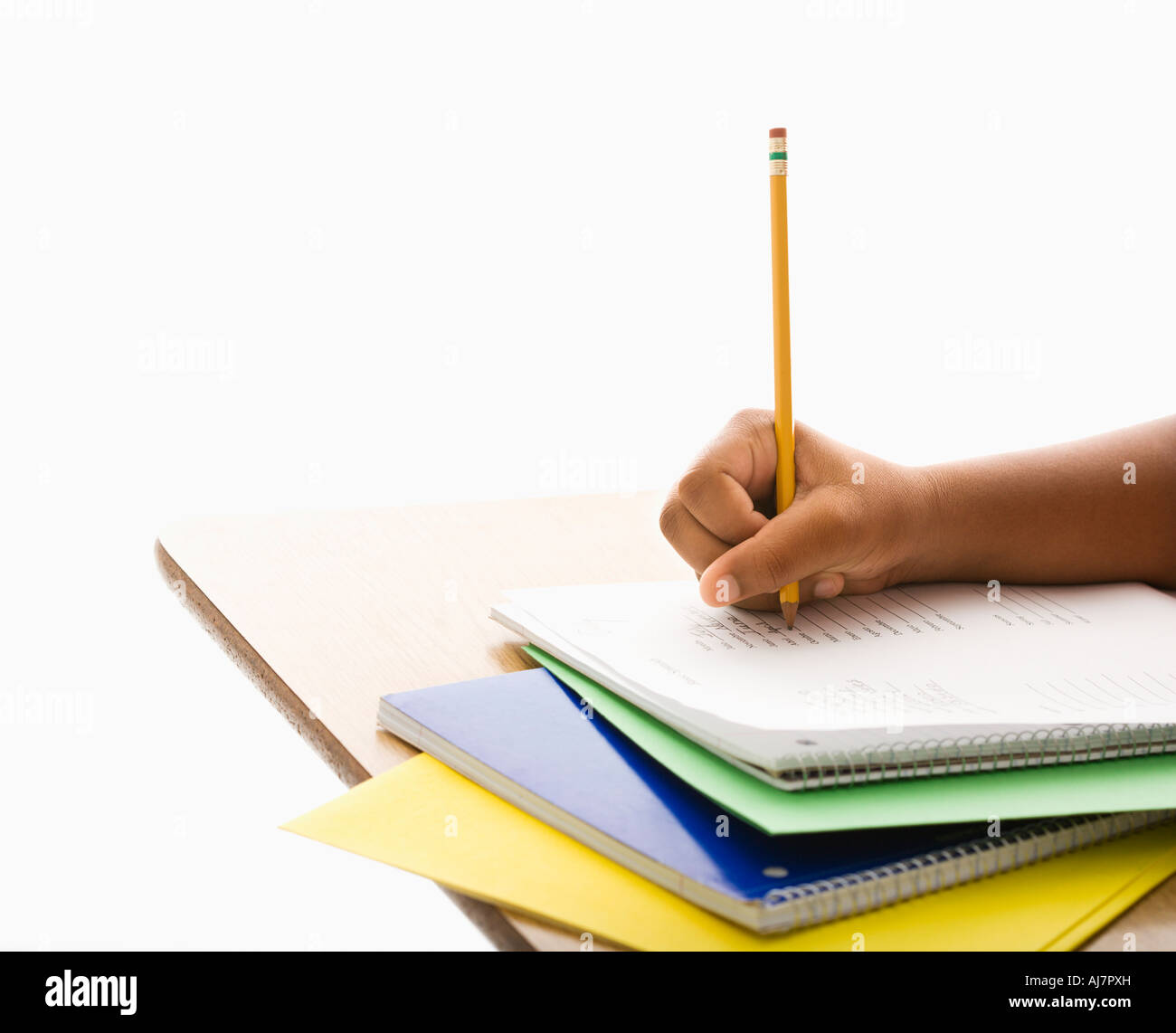 Hand of African American girl at school desk writing in notebook with