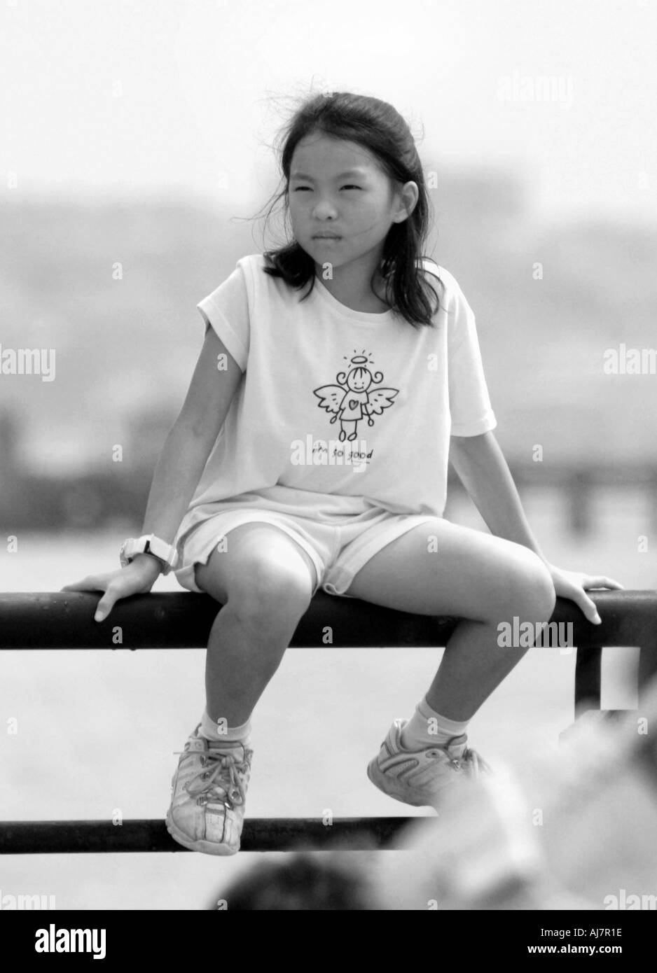 Asian girl sitting on fence at Liberty State Park Jersey City New Jersey Stock Photo