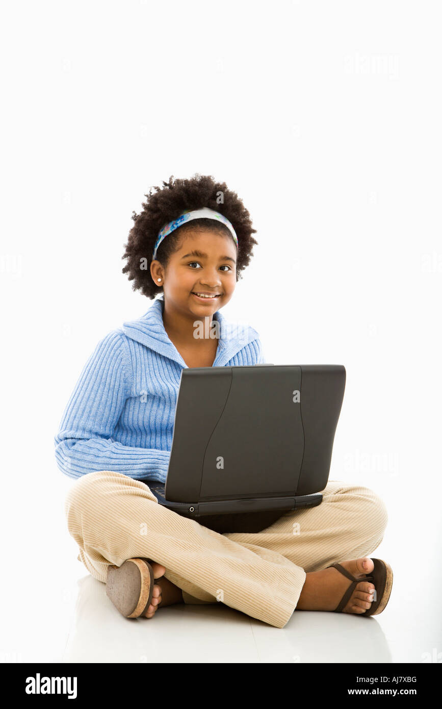 African American girl sitting on floor using laptop and smiling at ...