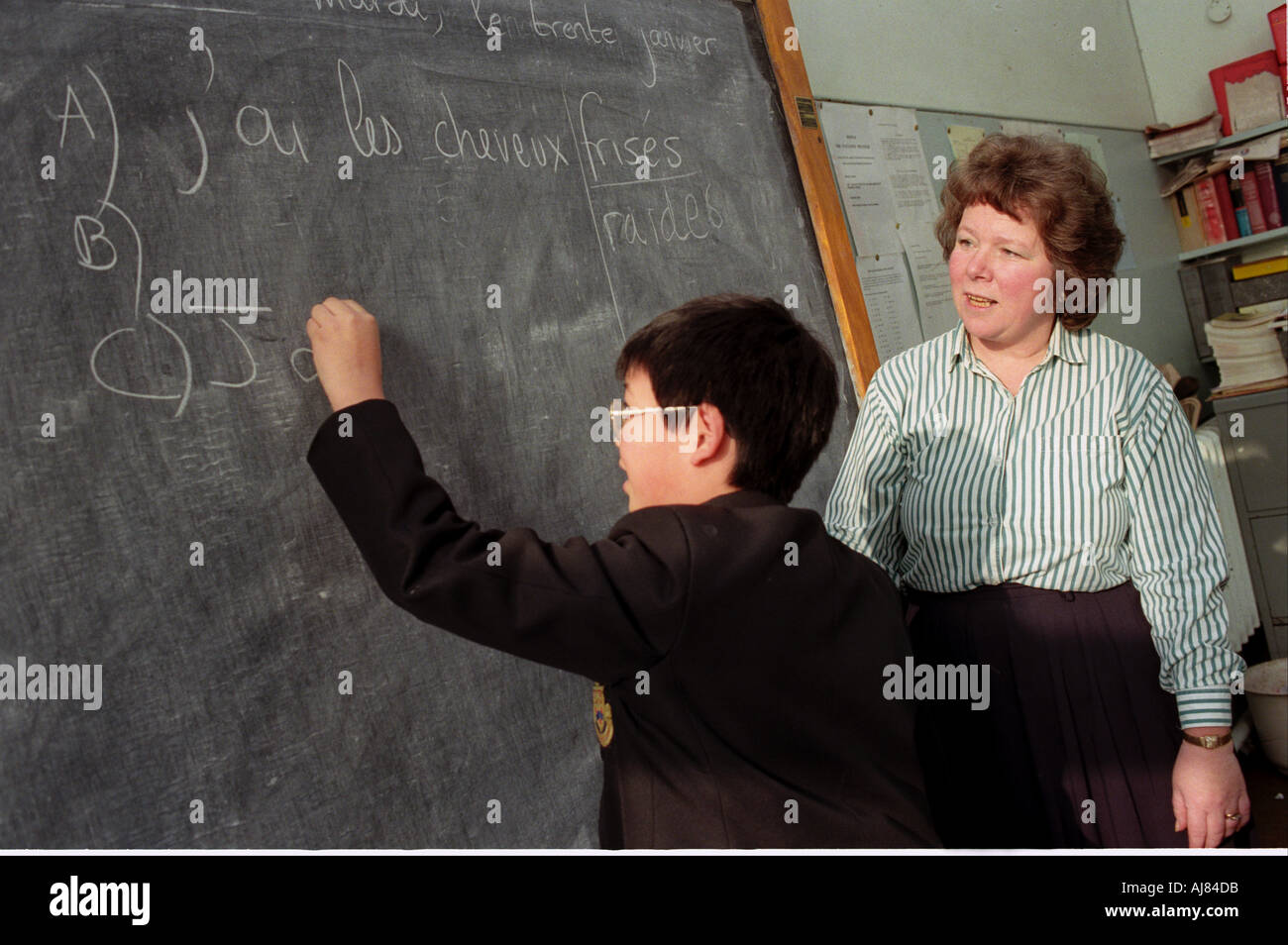 Young student writing on the blackboard during a French lesson. Stock Photo