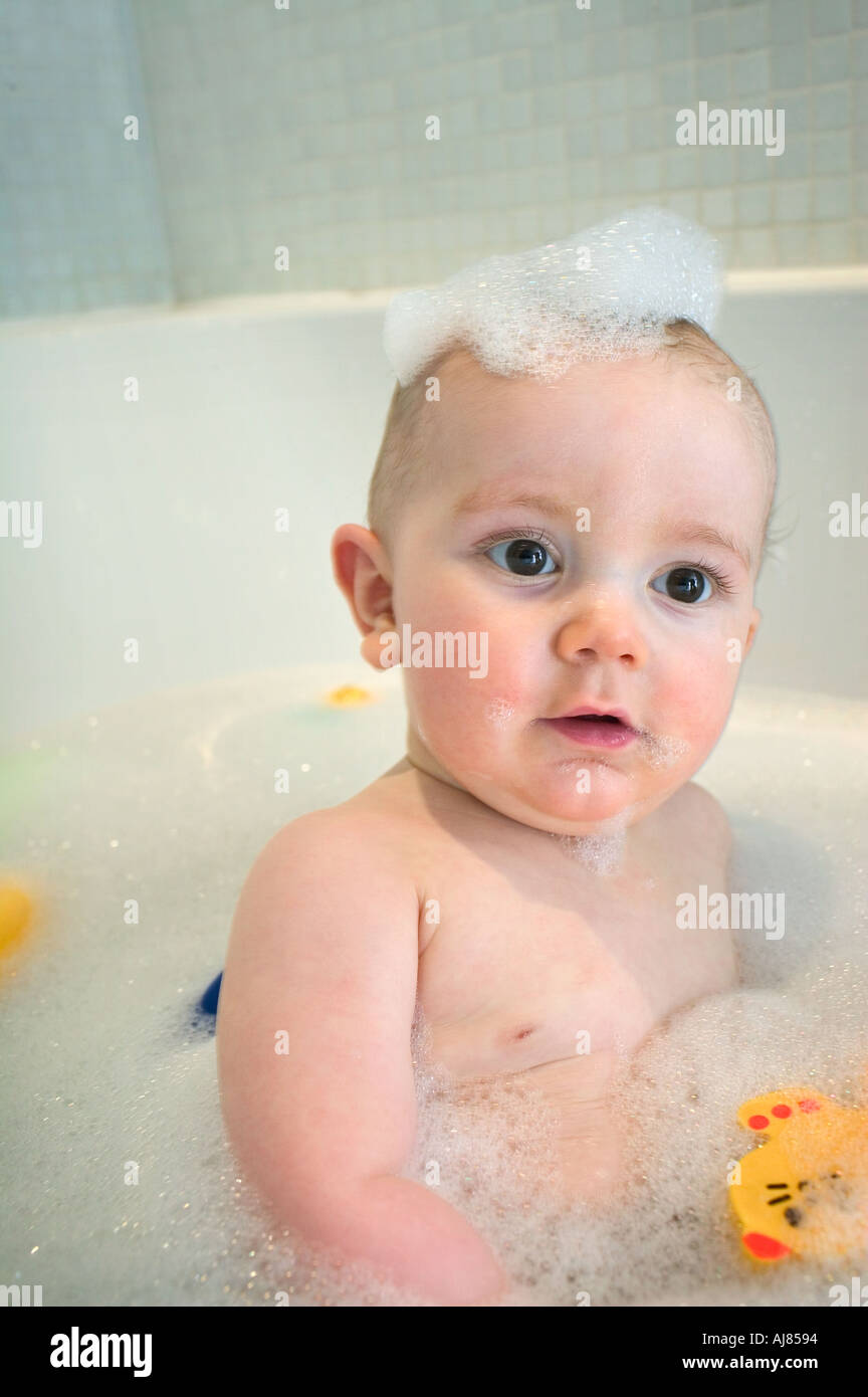 baby aged 8 months in the bath with soapy bubbles on his head Stock
