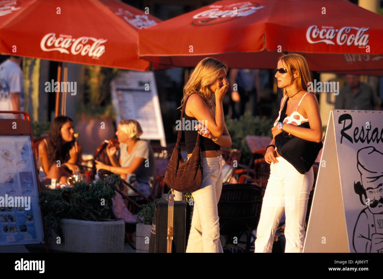 Two young women standing next to a pavement cafe Platja d en Bossa Ibiza City Ibiza Balearic Islands Spain Stock Photo