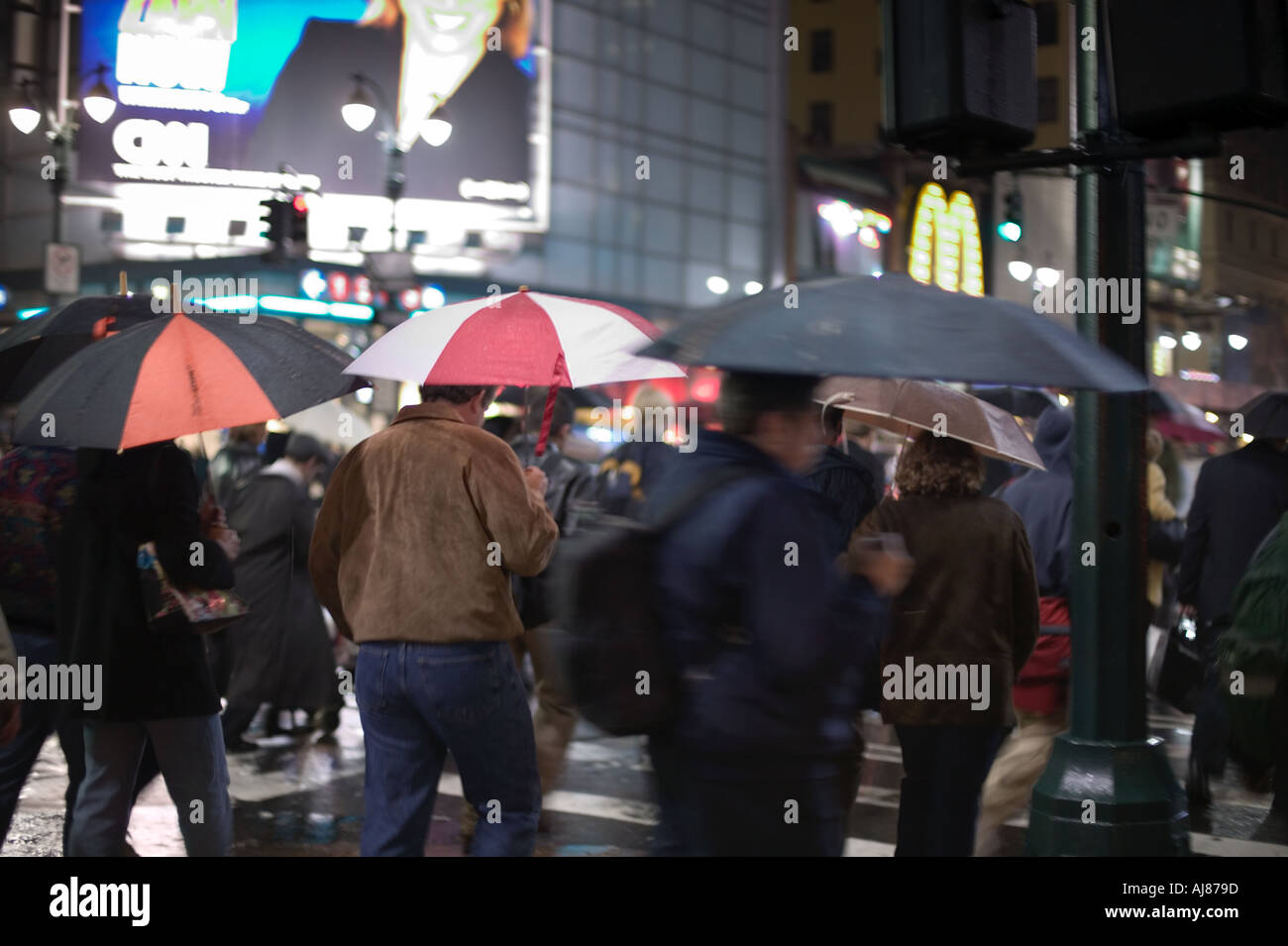 People with umbrellas on rainy night near Penn Station on Seventh Avenue and West 34th Street New York NY Stock Photo