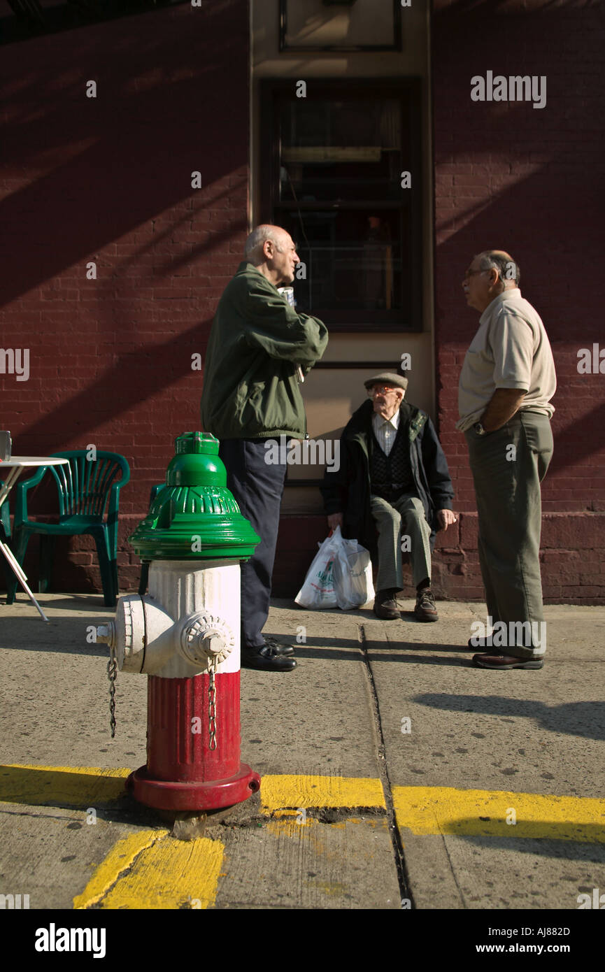 Sidewalk conversation between older men on Mulberry Street in Little Italy New York NY with fire hydrant painted with colors Stock Photo