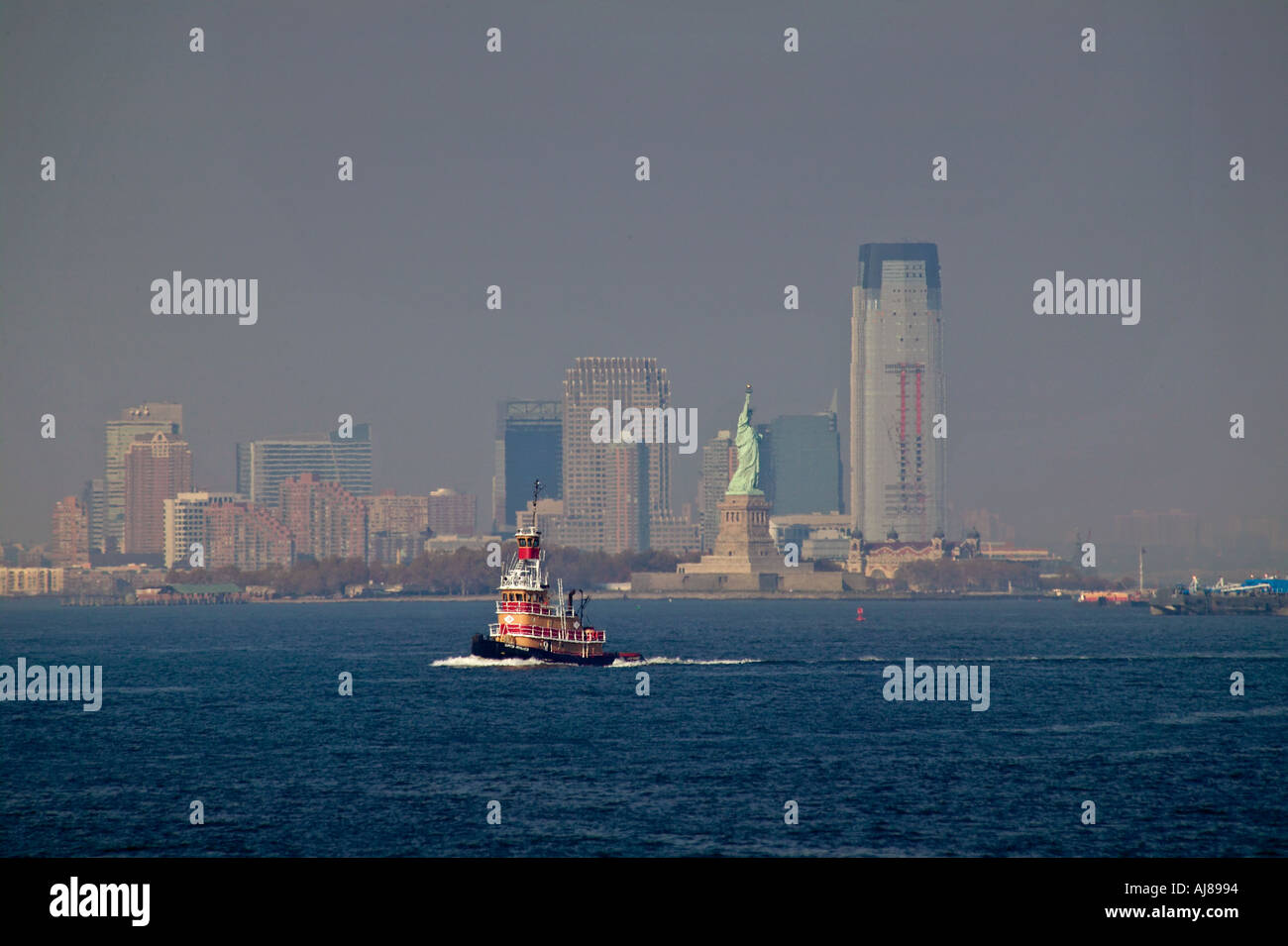 Tug boat on the Hudson River with Hoboken New Jersey skyline and Statue of Liberty in background Stock Photo