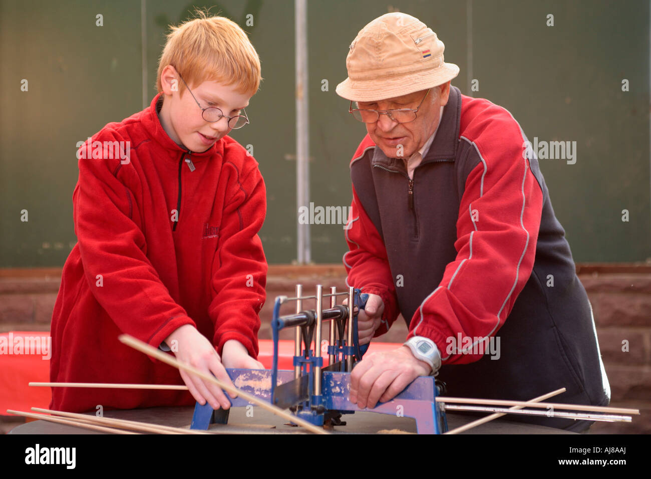 a grandfather teaching his grandson how to use a saw Stock Photo
