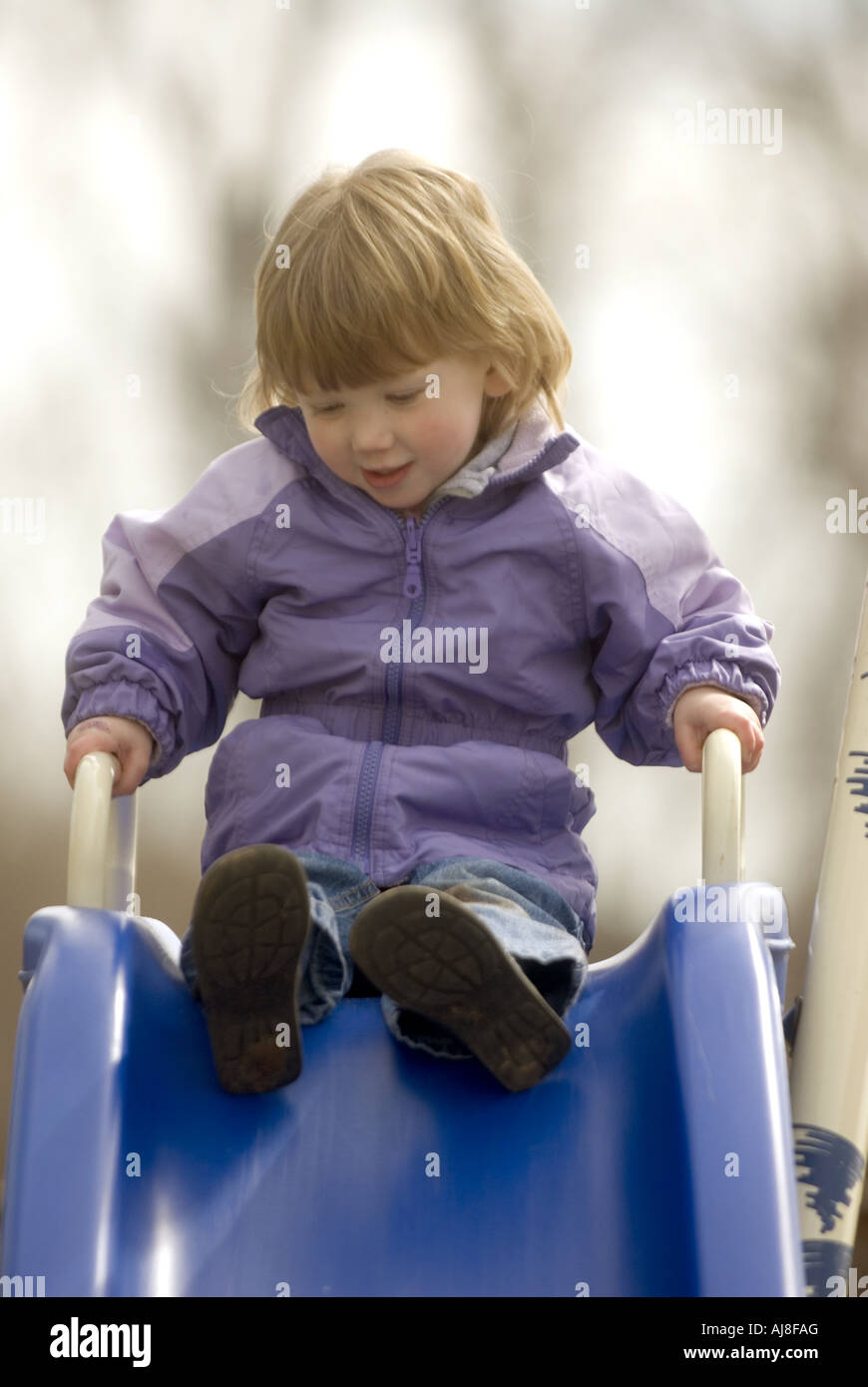 Little girl on slide playing at the playground on a cool day Stock ...
