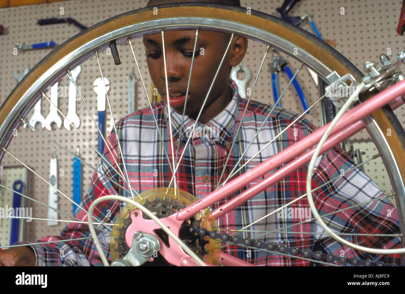 African American youth age 12 repairing a bicycle at Youth Express shop. St Paul Minnesota USA Stock Photo
