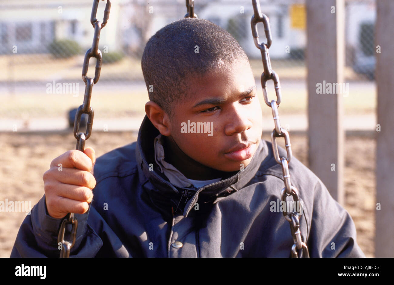 African American teen age 14 looking angry  sitting on a chain swing. St Paul Minnesota USA Stock Photo