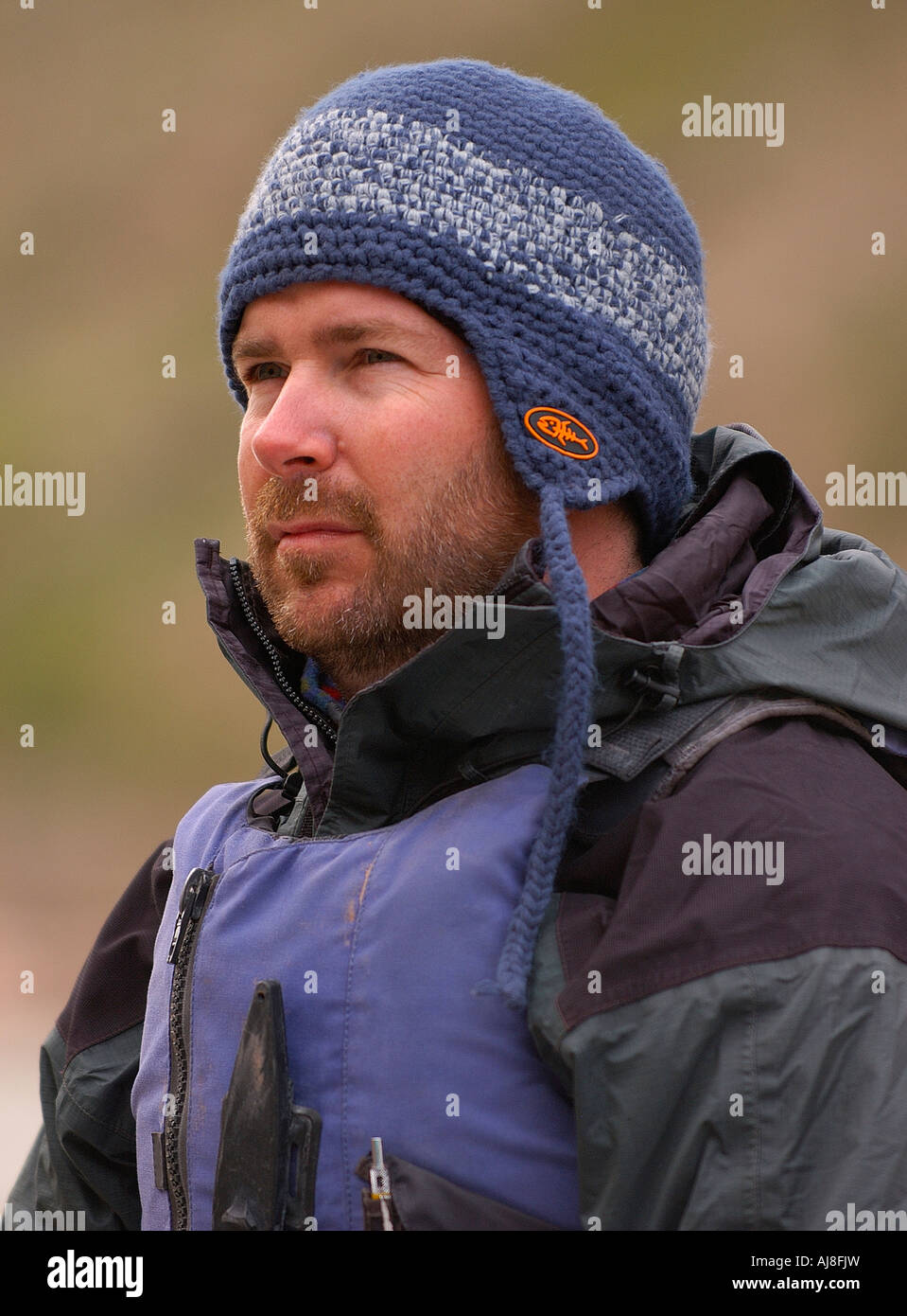 Man wearing a rain jacket and knit cap on a whitewater river rafting