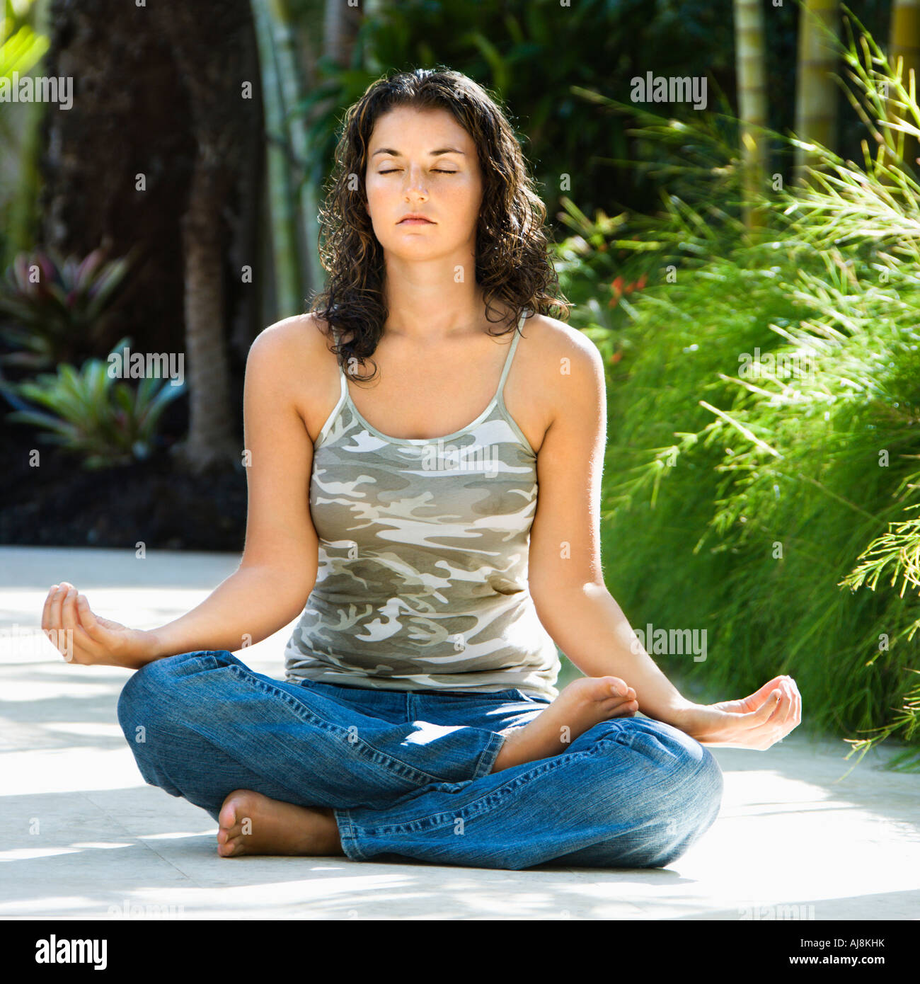 Pretty young adult Caucasian brunette woman sitting in lotus position ...