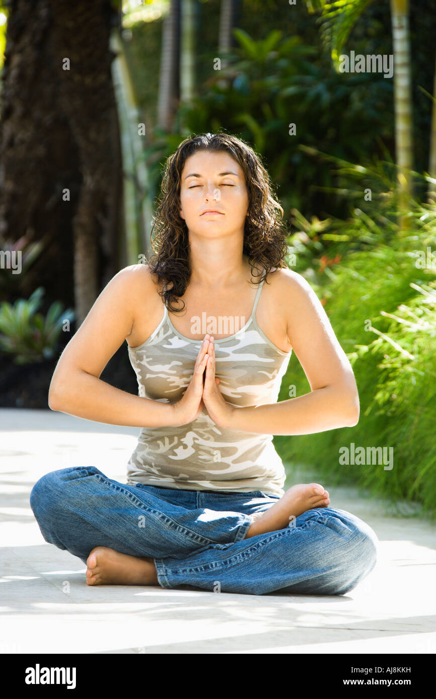 Pretty young adult Caucasian brunette woman sitting in lotus position ...