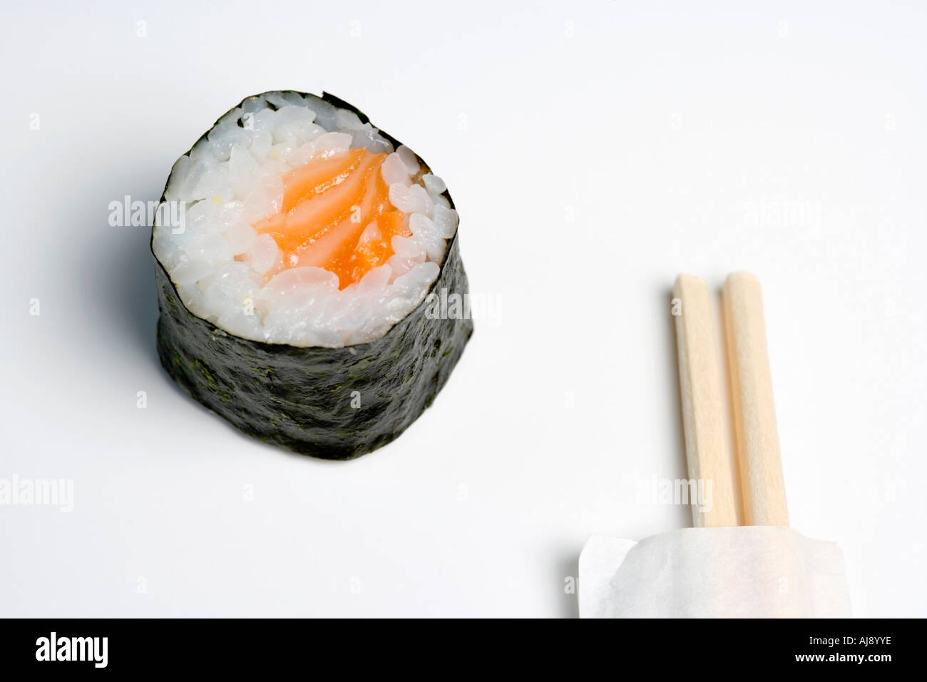 Wooden chopsticks next to salmon sushi piece Stock Photo
